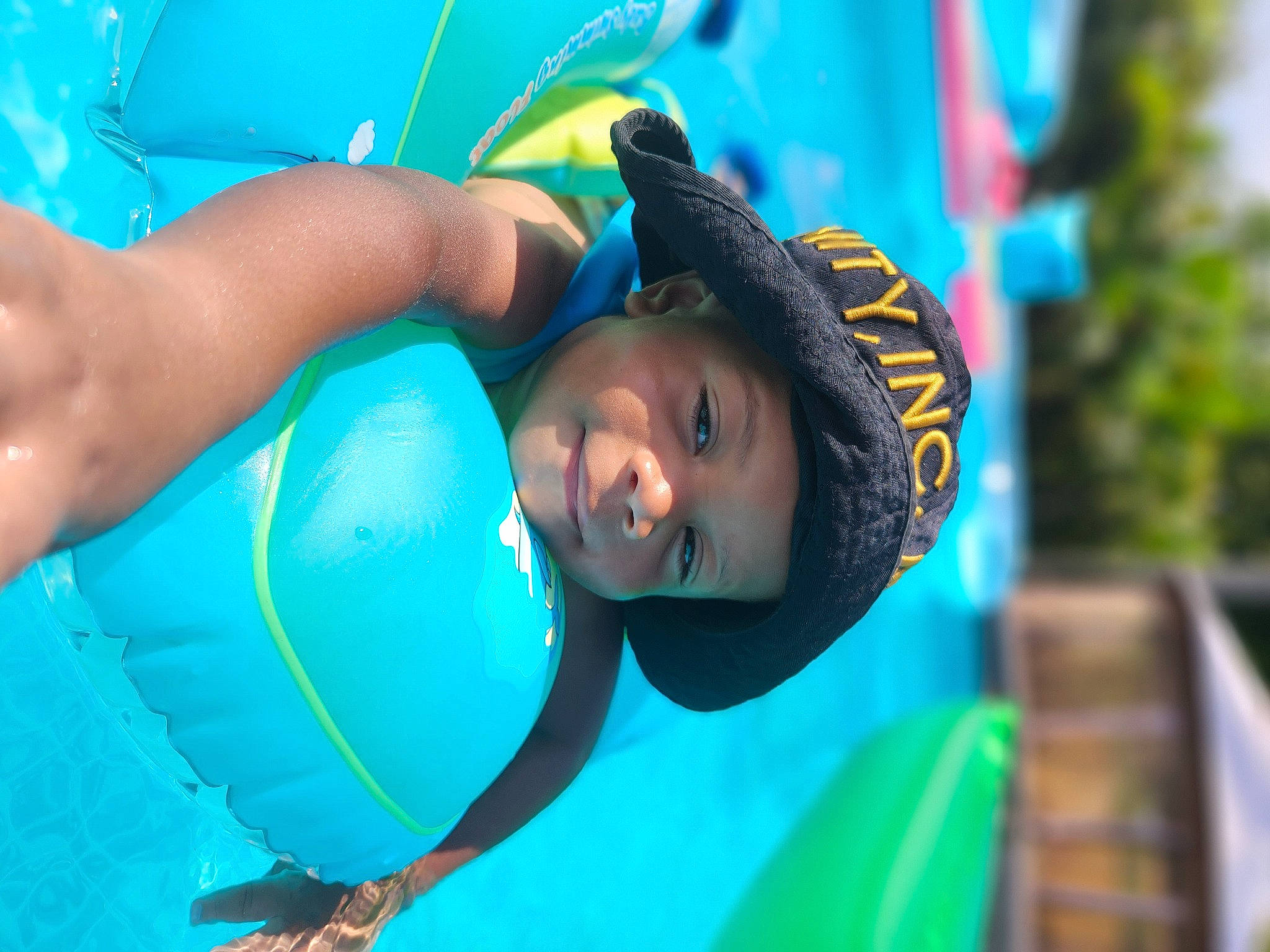 Hezekiah is registered to the contest to win money with this photo: amusement_park, child, electric_blue, fun, games, grass, happy, headgear, headwear, inflatable, leisure, person, personal_protective_equipment, play, recreation, smile, swimming_pool, swimwear, toddler, vacation