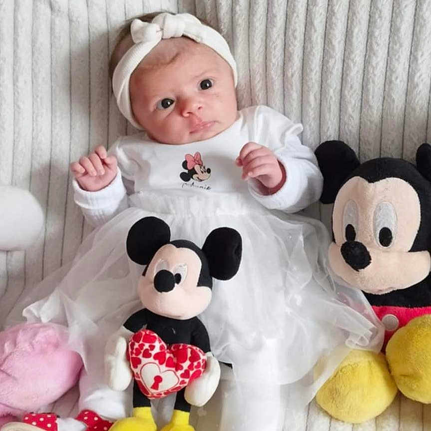 Giuliana participe au concours pour gagner de l'argent avec cette photo : adorable, baby, blanket, child, cute, headband, indoors, infant, lying_down, mickey_mouse, minnie_mouse, person, playful, plush_toy, portrait, smiling, soft_texture, stuffed_animal, toy, white_clothing