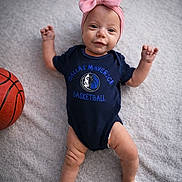 Roselinn is registered to the contest to win money with this photo: baby, basketball, blanket, child, cute, dallas_mavericks, happy, headband, indoor, infant, lying_down, newborn, onesie, person, pink_bow, portrait, smiling, socks, soft_texture, sports