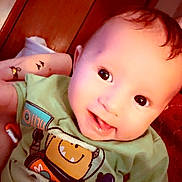 Levi joined the competition — help win amazing prizes! baby, child, smiling, green_shirt, robot_graphic, indoor, person, cute, happy, face, head, infant, young_child, toddler, clothing, portrait, skin, hair, eyes, mouth