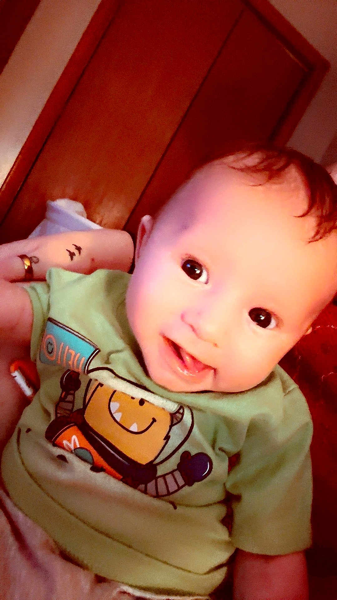Levi joined the competition — help win amazing prizes! baby, child, smiling, green_shirt, robot_graphic, indoor, person, cute, happy, face, head, infant, young_child, toddler, clothing, portrait, skin, hair, eyes, mouth