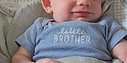 Ryder is registered to the contest to win money with this photo: baby, infant, child, smile, blue_shirt, little_brother, blanket, cushion, seat, indoor, comfortable, cozy, patterned_fabric, hand, head, face, skin, clothing, portrait, relaxed