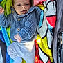 baby, infant, child, knitted_sweater, blue_sweater, pants, sock, colorful_blanket, fluffy_blanket, lying_down, tongue_out, cute, cozy, warm, playful, indoors, person, soft_texture, smiling, casual_clothing