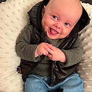 Tobias is registered to the contest to win money with this photo: baby, smiling, happy, infant, clothing, jeans, sweater, vest, socks, couch, cushion, soft_texture, indoor, portrait, cute, child, person, seated, face, hands