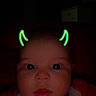 baby, face, child, neon_filter, devil_horns, dark_background, portrait, cute, expression, clothing, infant, indoor, closeup, head, eyes, mouth, red_clothing, glowing, digital_filter, baby_girl