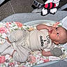 Amara is registered to the contest to win money with this photo: baby, infant, blanket, baby_rocker, plush_toy, carpet, clothing, socks, mittens, face, person, cute, lying_down, baby_garment, soft_toy, indoor, comfort, expression, newborn, resting
