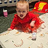 baby, carpet, child, crawling, crib, cute, expression, face, floor_mat, happy, indoor, nursery, person, playful, red_dress, smiling, sock, toddler, toy_seat, young_child