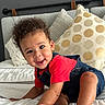 baby, bed, child, cozy, crawling, curly_hair, cute, denim_overalls, face, foot, furniture, hand, happy, indoors, person, pillow, red_shirt, skin, smiling, toddler