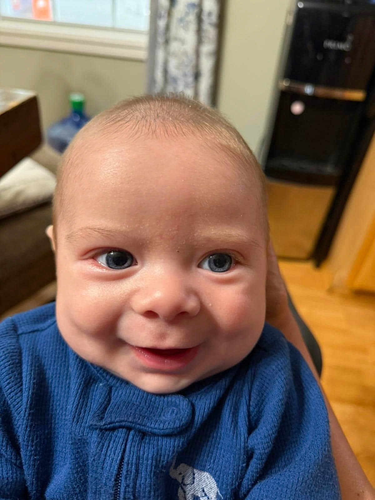 Tyler joined the competition — help win amazing prizes! baby, face, smile, blue_sweater, indoor, close_up, child, person, happy, eyes, cheeks, clothing, elephant_design, skin, head, infant, young_child, portrait, expression, cozy