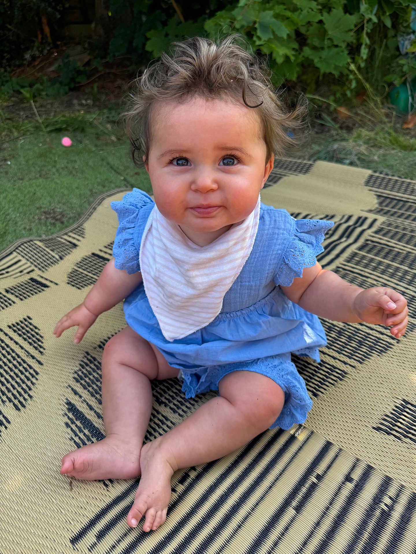 Holly joined the competition — help win amazing prizes! baby, child, sitting, outdoor, grass, mat, blue_dress, bib, cute, curly_hair, chubby_cheeks, smiling, person, infant, summer, playtime, barefoot, happy, portrait, nature