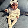 Holly joined the competition — help win amazing prizes! baby, infant, child, headband, bow, white_clothing, dress, tights, bed, pillow, blue_bedspread, curious_expression, sitting, indoors, soft_lighting, portrait, cute, small_hands, curly_hair, young_child