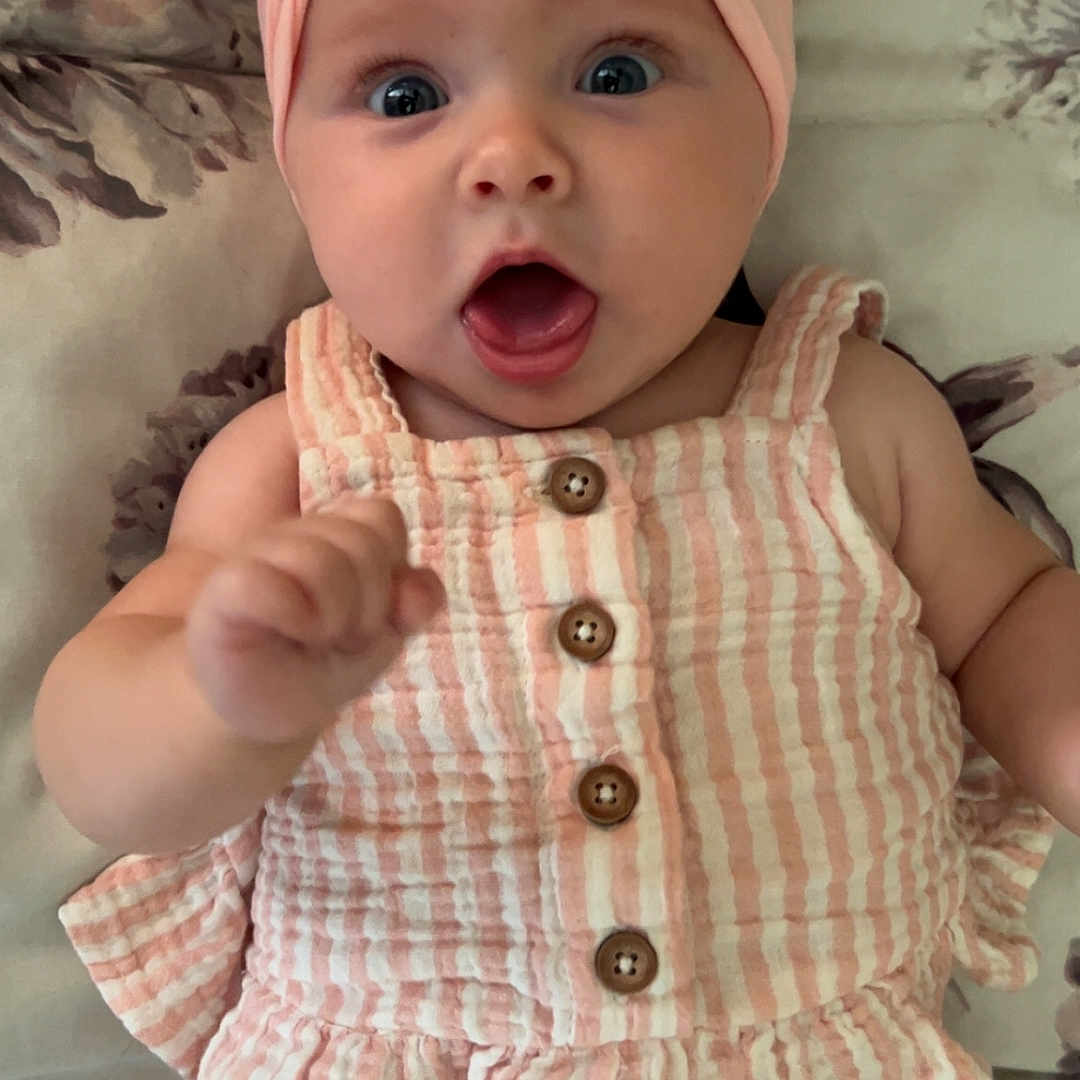 Amelia is registered to the contest to win money with this photo: adorable, baby, buttons, child, clothing, cute, expression, fingers, floral_blanket, hand, infant, lying_down, open_mouth, pink_headband, portrait, skin, striped_outfit, turban, wide_eyes, young_child