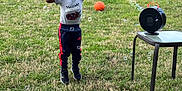 Amari is registered to the contest to win money with this photo: child, bubbles, bubble_machine, jumping, grass, backyard, basketball, table, fence, happy, outdoor, toy, play, person, smiling, casual_clothing, sneakers, daylight, greenery, fun