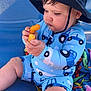 baby, blue_outfit, cheeks, cheesy_snack, child, chubby, closeup, colorful, curious, cute, food, hat, infant, outdoor, playful, sitting, snack, summer, sunhat, towel