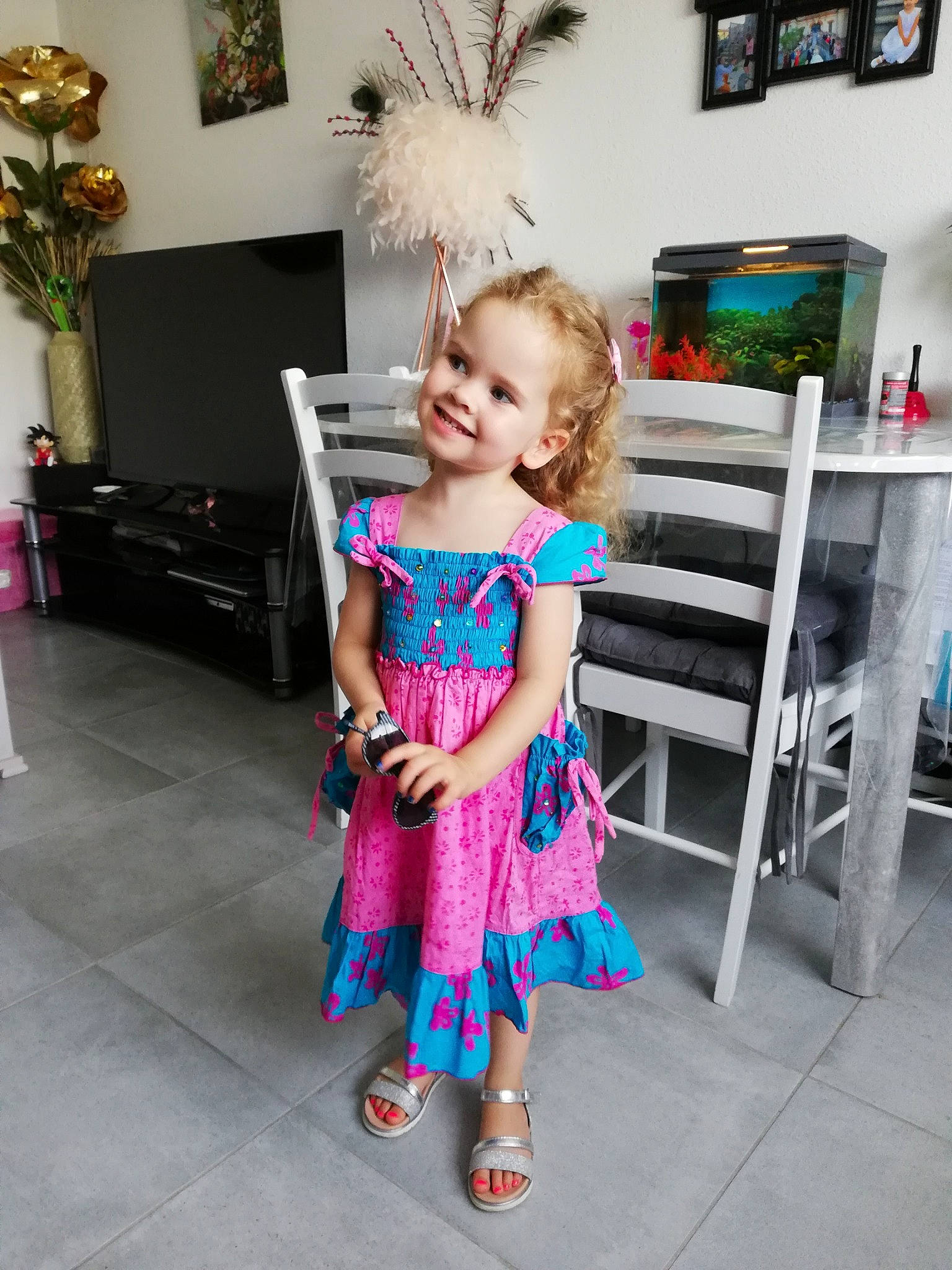 Angela participe au concours pour gagner de l'argent avec cette photo : baby_toddler_clothing, child, dress, electric_blue, event, fashion_accessory, fashion_design, flooring, fun, happy, houseplant, joy, magenta, pattern, person, picture_frame, pink, plant, room, sandal