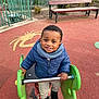 bench, child, clothing, fence, footwear, greenery, happy, jacket, metal, outdoor, park, person, play_area, playground, rubber_flooring, scarf, smile, spring_rider, toddler, toy