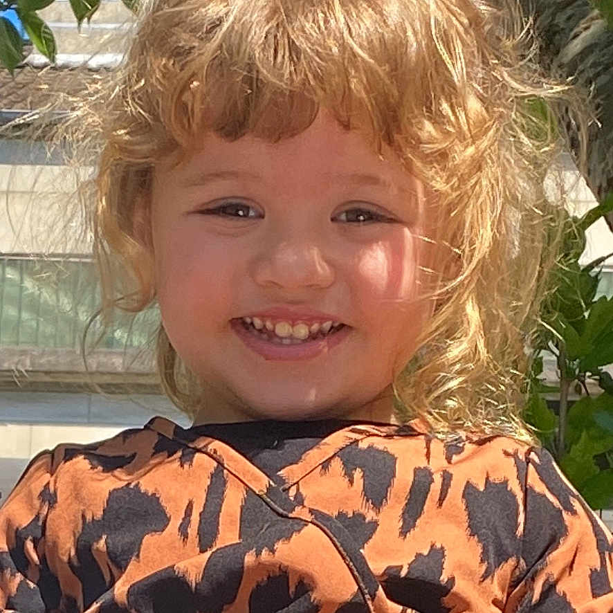 Assil a rejoint le concours — aidez-le/la à gagner de superbes lots ! child, smiling, blonde_hair, curly_hair, dress, orange_dress, patterned_clothing, outdoor, tree, leaves, sunny, happy, portrait, person, nature, daylight, face, cute, young_child, fashion