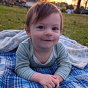 Walter is registered to the contest to win money with this photo: child, baby, infant, smiling, outdoors, park, blanket, plaid_blanket, onesie, hands, face, eyes, grass, sunset, portrait, cute, toddler, young_child, blanket_pattern, relaxing