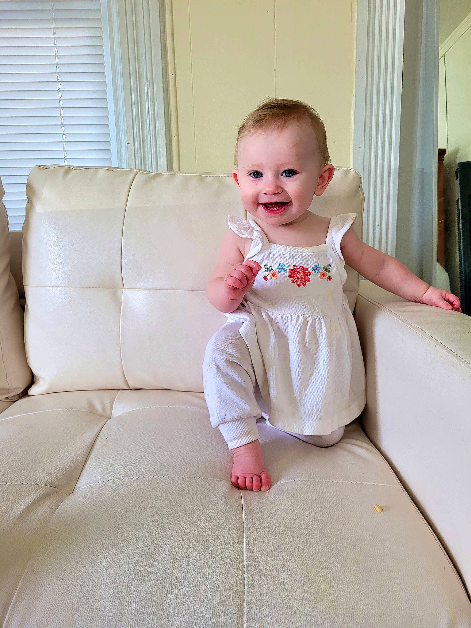 Josephine is registered to the contest to win money with this photo: baby, baby_toddler_clothing, cheek, comfort, couch, curtain, dress, face, finger, flash_photography, floor, flooring, happy, joint, joy, one_piece_garment, person, shoulder, skin, sleeve