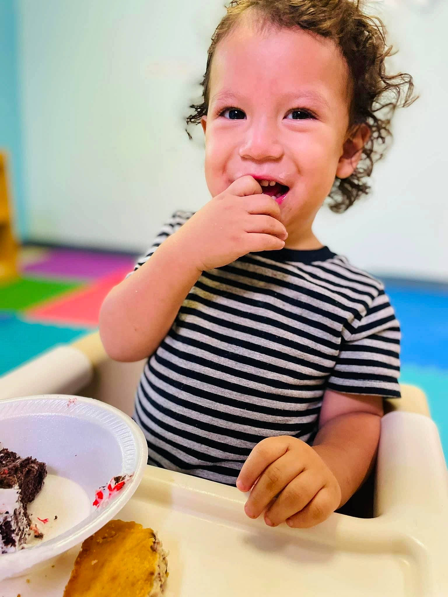Jose is registered to the contest to win money with this photo: baby_toddler_clothing, chair, cuisine, dish, dishware, face, finger, food, food_craving, gesture, happy, ingredient, person, plate, recipe, smile, sweetness, table, tableware, toddler