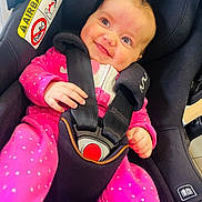 Bethany is registered to the contest to win money with this photo: baby, car_seat, infant, pink_clothing, smiling, happy, child, seat_belt, safety, indoor, cute, face, person, young_child, head, infant_clothing, car_seat_harness, sitting, bright_eyes, black_car_seat
