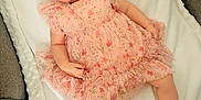 Bethany is registered to the contest to win money with this photo: baby, child, infant, smiling, pink_dress, headband, blanket, couch, carpet, socks, shoes, happy, portrait, cute, indoor, person, toddler, soft_texture, floral_pattern, lying_down
