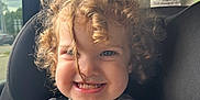 Hollyann joined the competition — help win amazing prizes! child, toddler, curly_hair, car_seat, seatbelt, smiling, sweater, daisy_pattern, indoors, car_interior, window, sunlight, happy, face, person, cute, portrait, baby, safety, seat