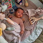 Gabriel participe au concours pour gagner de l'argent avec cette photo : baby, infant, blanket, toy, play_mat, stuffed_animal, giraffe_toy, pacifier, rattle, soft_toy, child, indoors, floor, cute, portrait, lying_down, cozy, colorful, clothing, face
