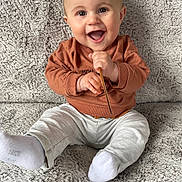 Clovis participe au concours pour gagner de l'argent avec cette photo : baby, child, smiling, happy, sitting, couch, clothing, socks, sweatshirt, pants, face, hands, indoor, texture, soft, cute, person, expression, joy, infant