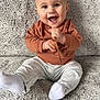 baby, child, smiling, happy, sitting, couch, clothing, socks, sweatshirt, pants, face, hands, indoor, texture, soft, cute, person, expression, joy, infant