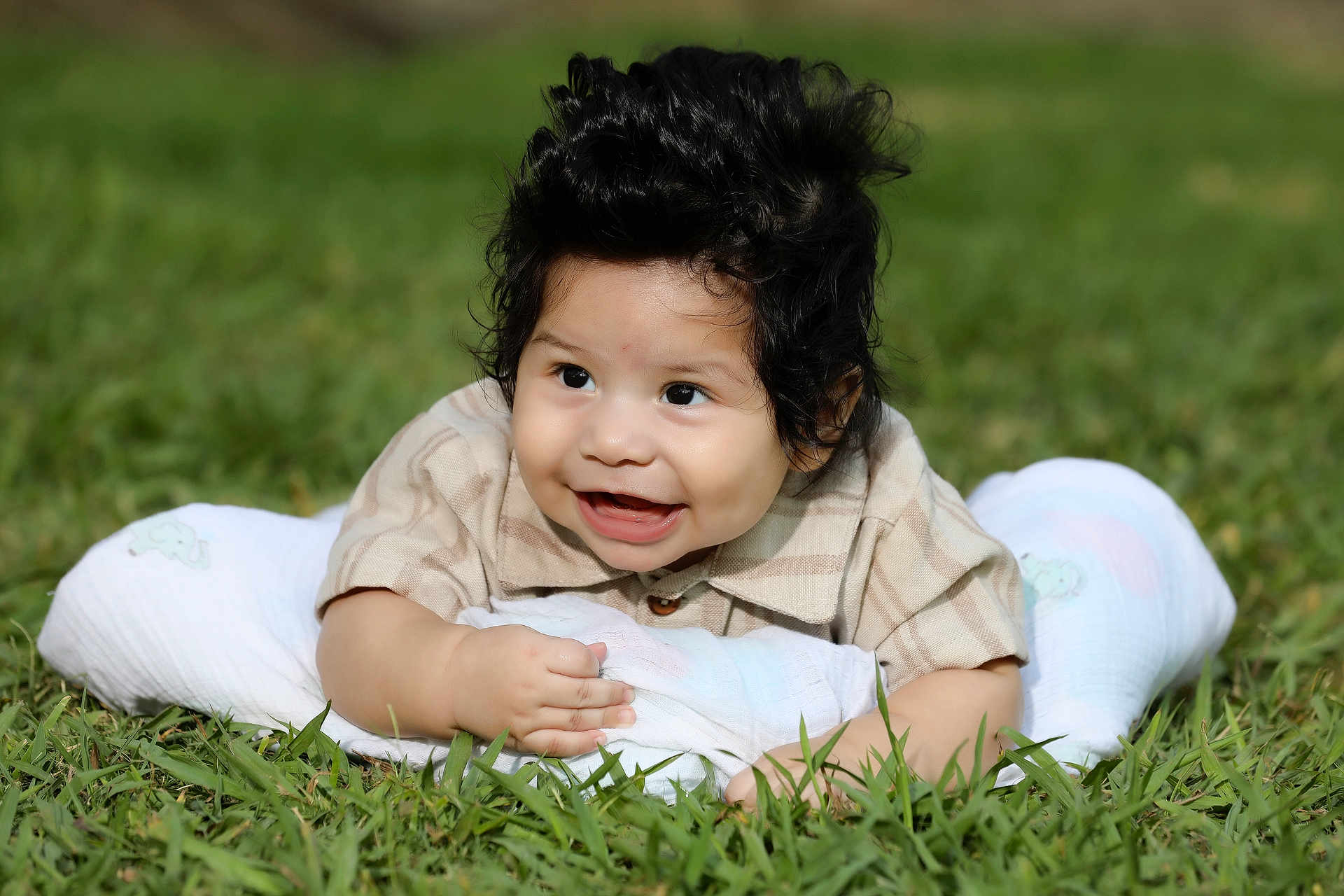 Ezekiel is registered to the contest to win money with this photo: baby, smiling, grass, blanket, shirt, child, happy, face, outdoor, infant, portrait, cute, toddler, nature, young, lying_down, fun, skin, person, casual_clothing