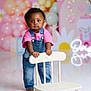 Reign is registered to the contest to win money with this photo: toddler, child, denim_overalls, pink_shirt, barefoot, white_chair, balloons, party, birthday, decorations, daisies, lights, studio, floor_reflection, portrait, standing, cute, indoor, baby, serious_face