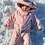 Sutton is registered to the contest to win money with this photo: baby, child, snow, winter, cold, pink_onesie, hood, bear_ears, footed_pajamas, outdoor, cute, infant, face, blue_eyes, plush, warm_clothing, lying_down, frost, winter_wear, portrait