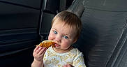 Sutton is registered to the contest to win money with this photo: baby, child, car_seat, interior, blue_eyes, food, crumbs, clothing, onesie, window, sky, cloud, seatbelt, car, person, sitting, cute, infant, hand, foot