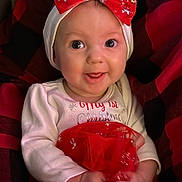 Sutton is registered to the contest to win money with this photo: baby, child, infant, smiling, red_bow, headband, christmas, holiday, festive, tutu, white_clothing, cute, happy, portrait, sitting, plaid_background, hands, eyes, face, indoors