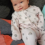 Violet joined the competition — help win amazing prizes! baby, infant, onesie, smiling, face, couch, quilt, patchwork, pink_clothing, cartoon_print, relaxed, indoors, cute, child, young, soft_lighting, seated, comfort, cozy, portrait