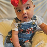 Aurora joined the competition — help win amazing prizes! baby, child, red_bow, denim_overalls, patches, curious_eyes, sitting, cushion, soft_background, infant, cute, portrait, closeup, clothing, hand, face, headband, indoor, person, young_child