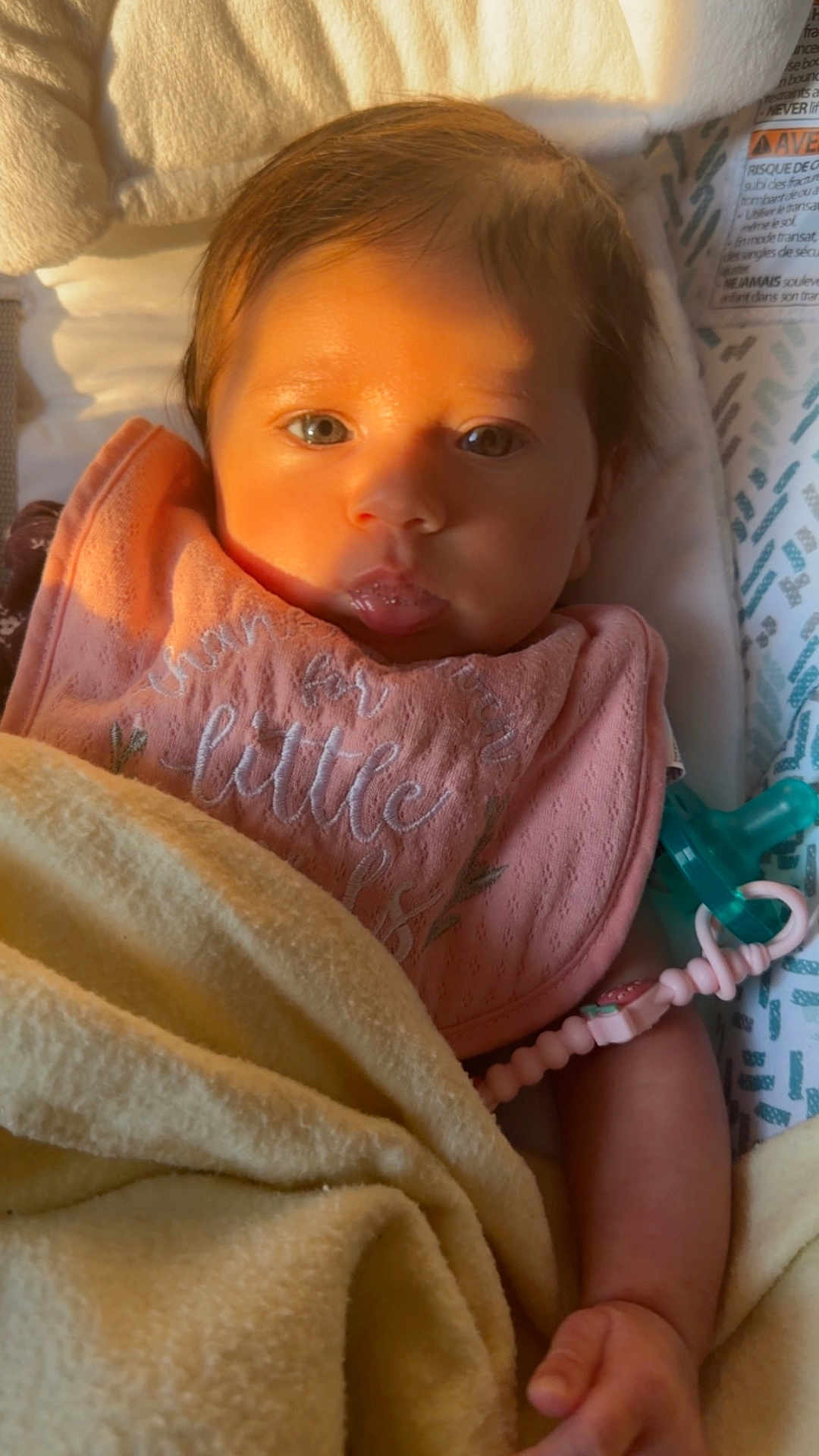 Nathalia is registered to the contest to win money with this photo: baby, infant, blanket, pink_bib, pacifier, face, eyes, hand, cozy, soft_lighting, indoors, child, newborn, cute, portrait, close_up, skin, expression, peaceful, sleeping_area