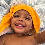 Saheim is registered to the contest to win money with this photo: toddler, child, smile, happy, face, teeth, orange_towel, blanket, quilt, skin, bare_chest, earring, closeup, portrait, indoor, cute, baby, expression, joy, relaxation