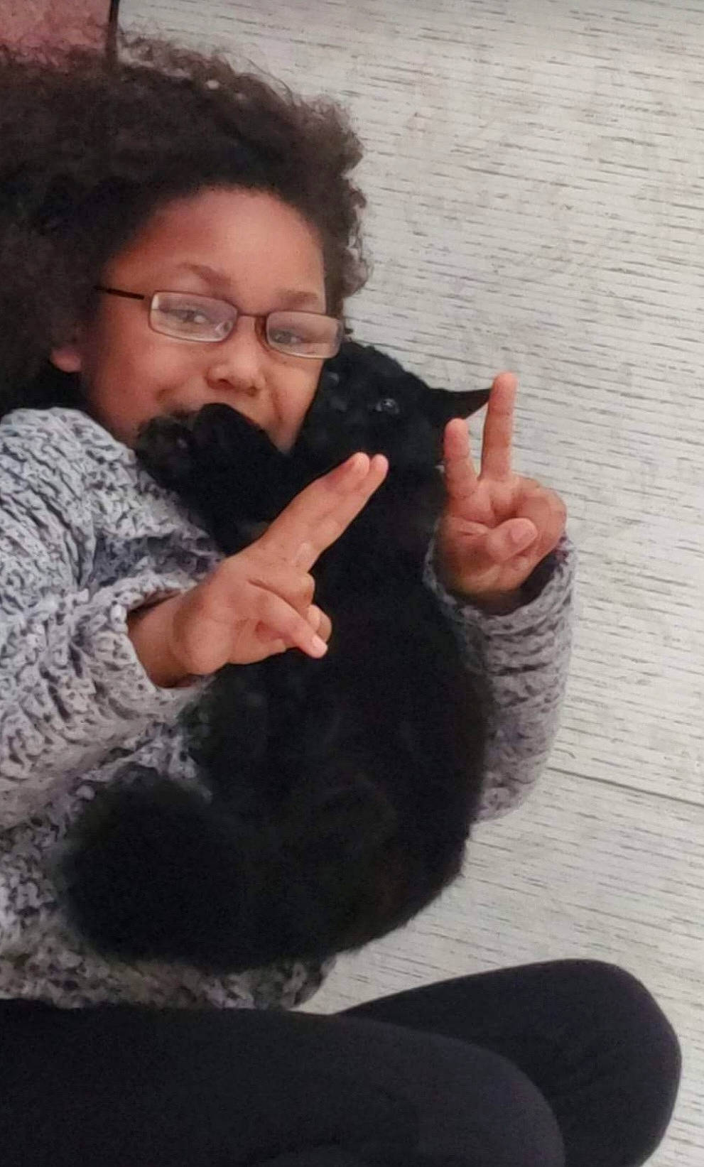 Paris is registered to the contest to win money with this photo: beard, cat, elbow, eyewear, felidae, finger, fur, gesture, glasses, hand, moustache, nose, person, sign_language, sitting, small_to_medium_sized_cats, thumb, vision_care, whiskers