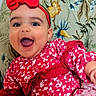 baby, child, smiling, happy, red_bow, red_dress, floral_pattern, chair, portrait, cute, indoors, person, headwear, toddler, sitting, bright_colors, joyful, cute_expression, fashion, closeup