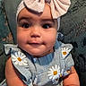baby, child, infant, headband, bow, dress, flower_pattern, bracelet, arm, chubby, cute, seated, indoors, furniture, portrait, smile, face, eyes, person, closeup