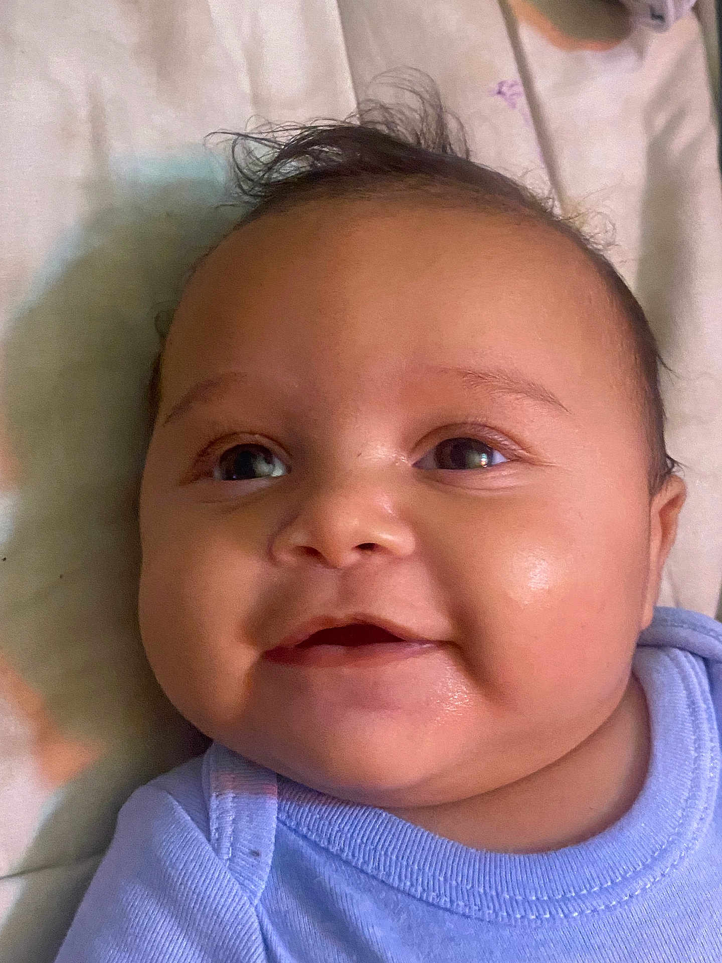 Adonis is registered to the contest to win money with this photo: baby, smiling, face, closeup, infant, child, cute, happy, skin, person, portrait, clothing, blue, lying_down, indoors, young, head, eyes, cheeks, toddler