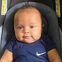 baby, infant, car_seat, child, blue_shirt, nike_logo, portrait, face, cute, chubby_cheeks, moawk_hair, comfortable, seat_belt, indoor, young_child, looking_at_camera, clothing, person, head, expression