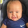baby, infant, smiling, face, blue_clothing, nike_logo, car_seat, warning_label, cute, happy, child, portrait, indoor, young, person, head, skin, eyes, mouth, hair
