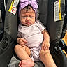 baby, infant, car_seat, purple_bow, headband, onesie, serious_expression, child, indoor, person, skin, foot, hand, seat, straps, warning_label, clothing, cute, portrait, young_child