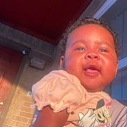 Lormanii Chanell joined the competition — help win amazing prizes! baby, child, person, smiling, sunlight, hand, shirt, minnie_mouse, cartoon, brick_wall, door, window, curly_hair, outdoor, happy, cute, infant, skin, holding, portrait