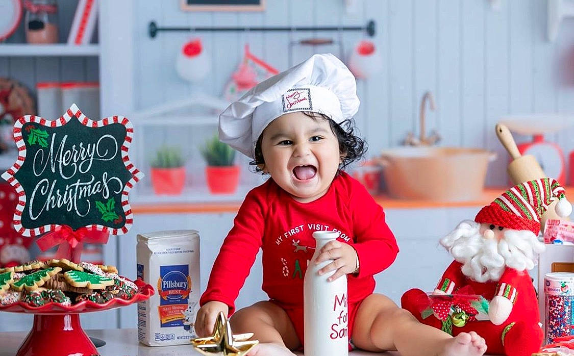 Logan is registered to the contest to win money with this photo: child, christmas, christmas_decoration, christmas_eve, fictional_character, food, happy, headwear, holiday, party_hat, person, toddler