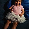baby, girl, smiling, pink_clothing, white_skirt, blue_cushion, hair_bows, sandals, dimples, happy, child, indoors, cute, infant, tutu, feet, person, portrait, seated, soft_lighting