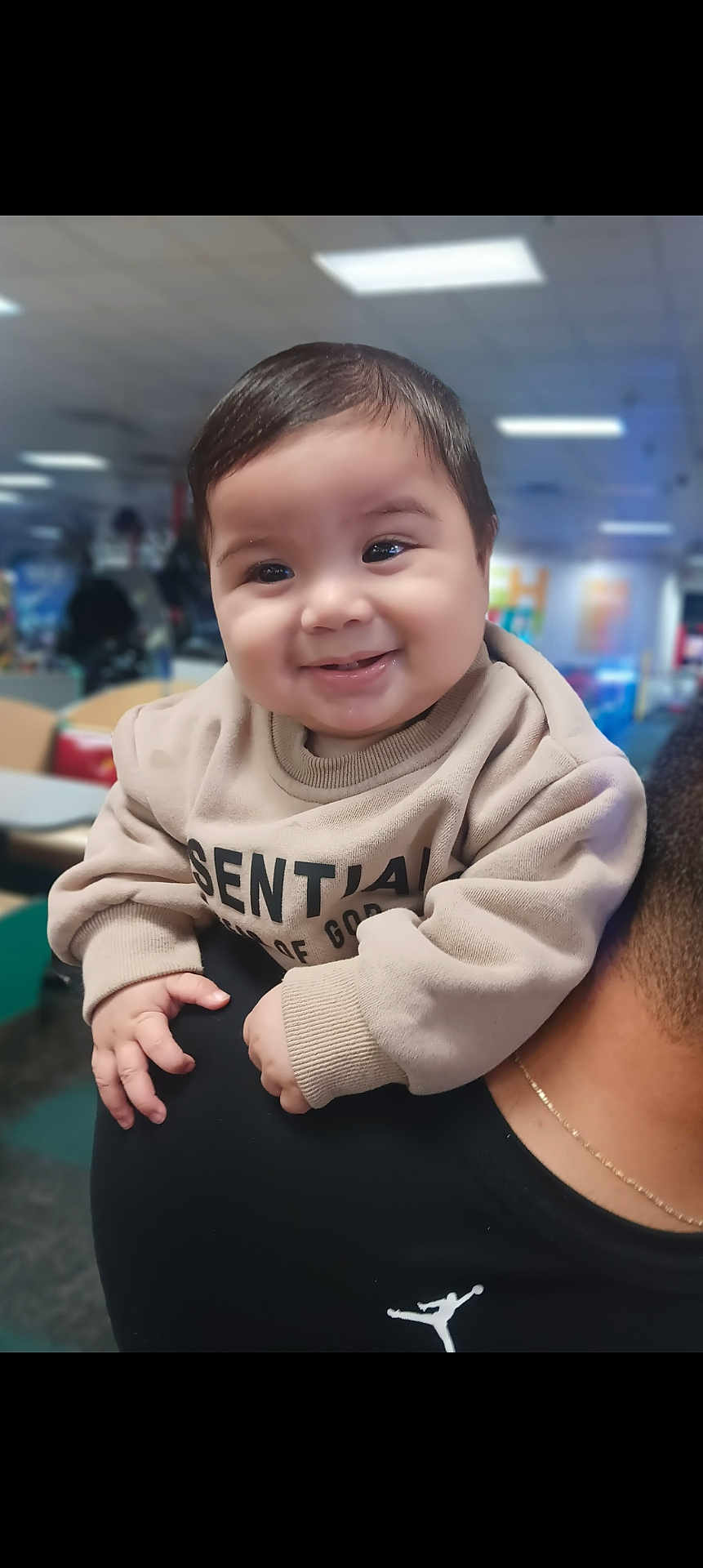 Michael joined the competition — help win amazing prizes! baby, child, smile, indoor, person, face, clothing, hand, shoulder, hair, cute, happy, young, infant, sweatshirt, holding, portrait, warm, black_shirt, blurred_background